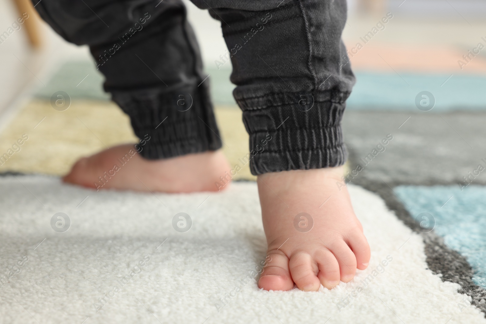 Photo of Baby walking on soft carpet, closeup view