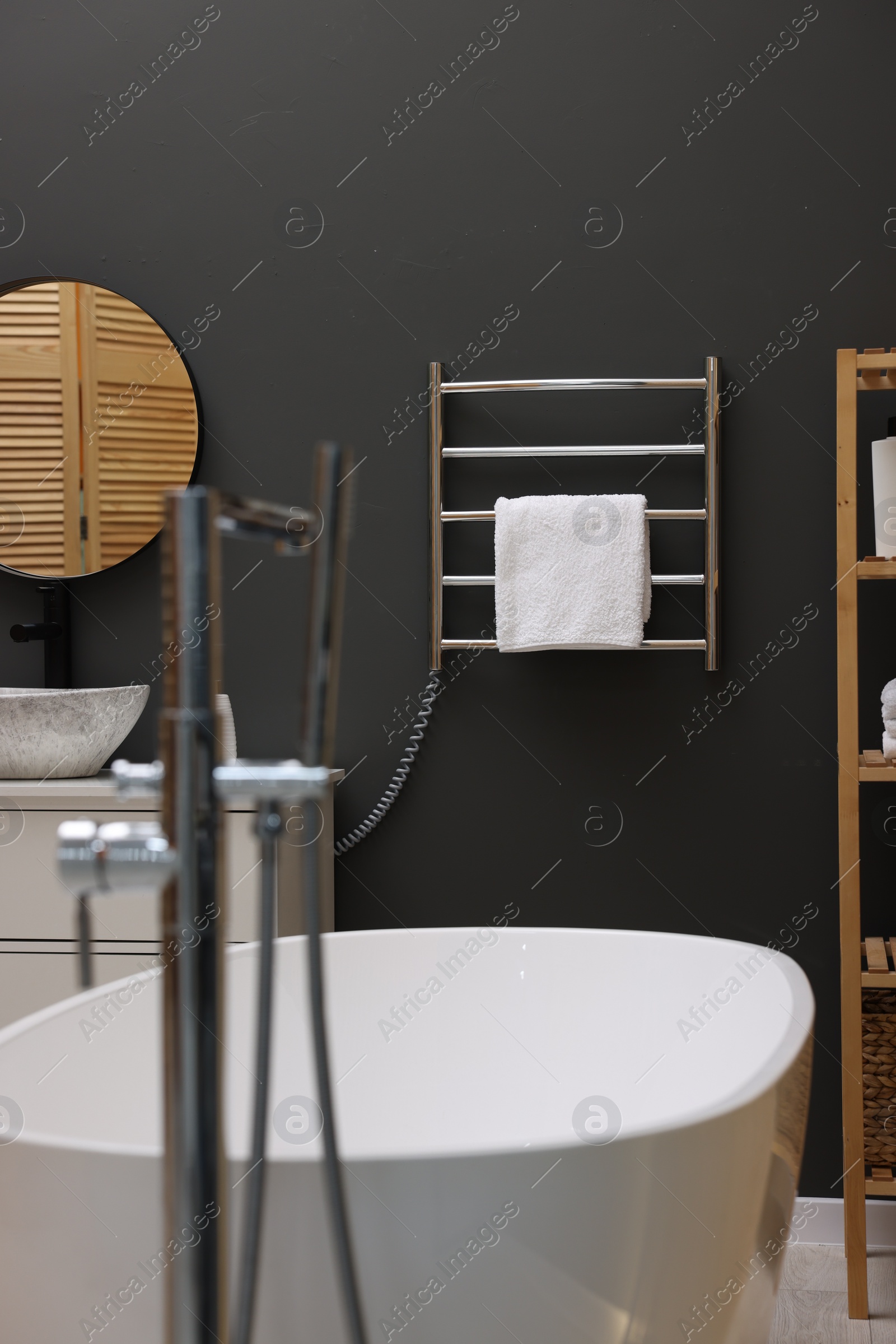 Photo of Stylish bathroom interior with heated towel rail and white tub