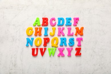 Photo of Colorful magnetic letters on white textured background, flat lay. Alphabetical order