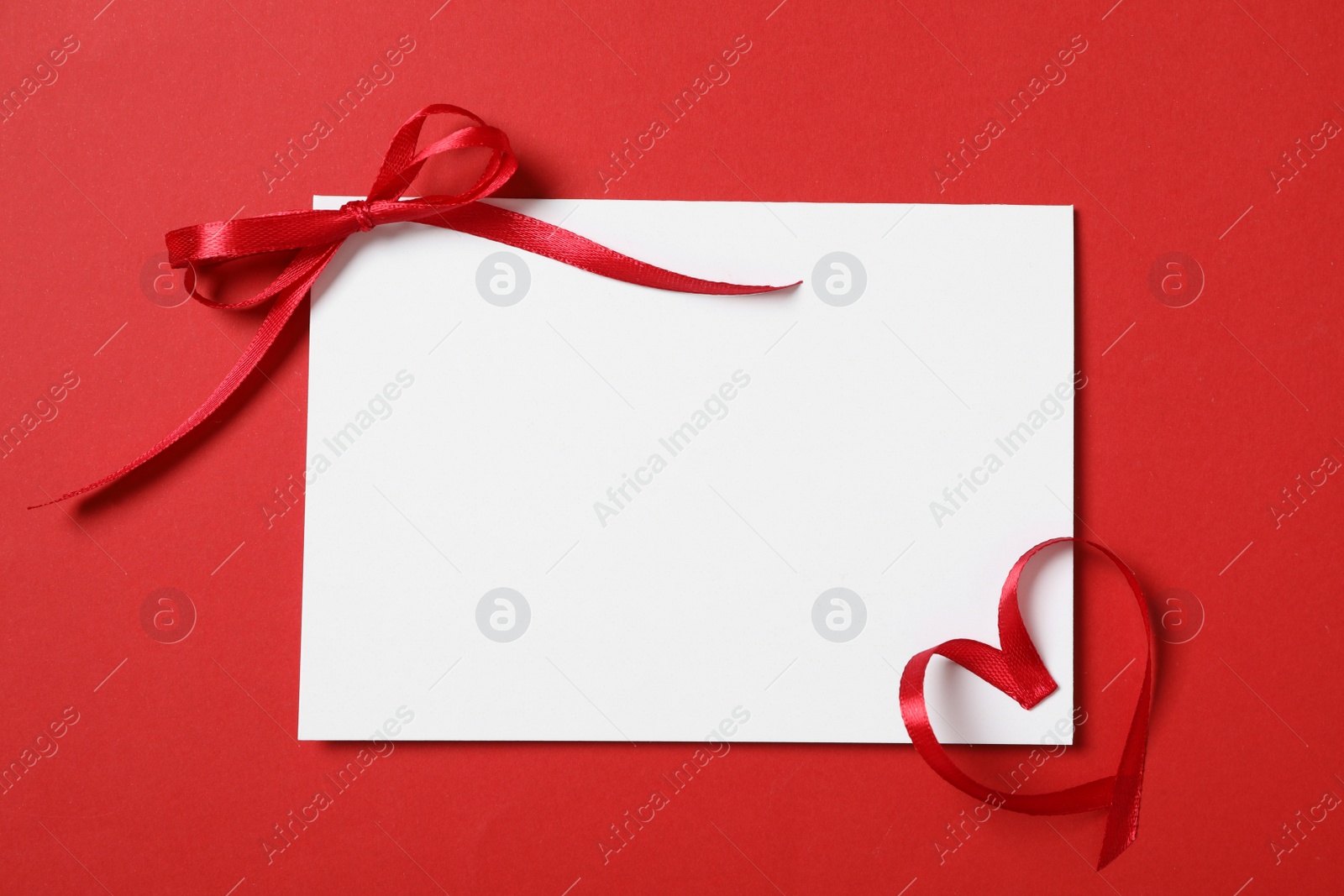 Photo of Blank card and ribbons on red background, flat lay with space for text. Valentine's Day celebration