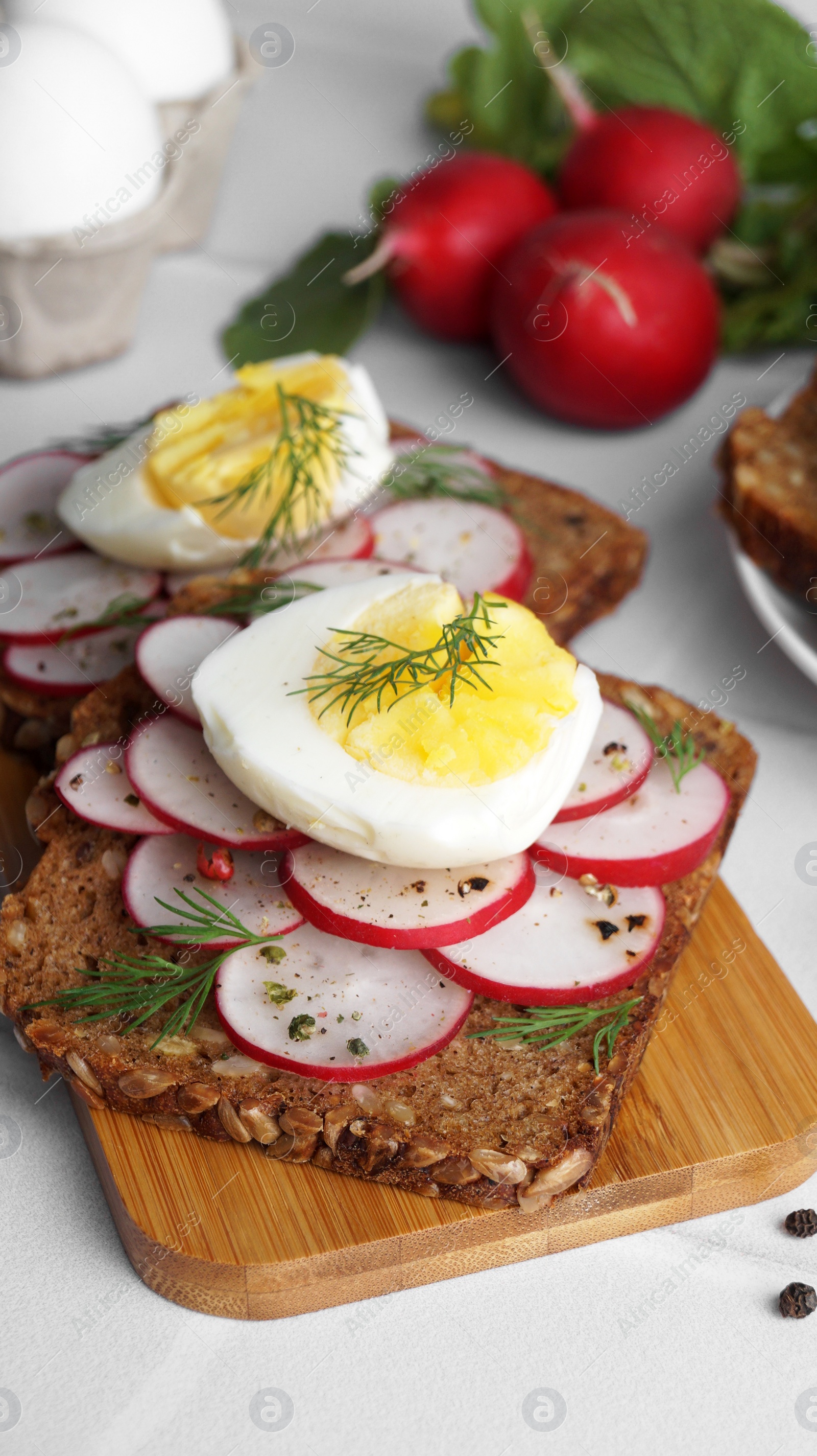 Photo of Tasty sandwiches with boiled egg and radish on white table, closeup