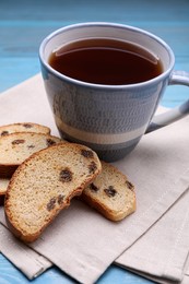 Photo of Sweet hard chuck crackers with raisins and cup of tea on light blue wooden table