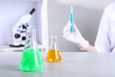 Photo of Glassware with samples on table and assistant in chemistry laboratory