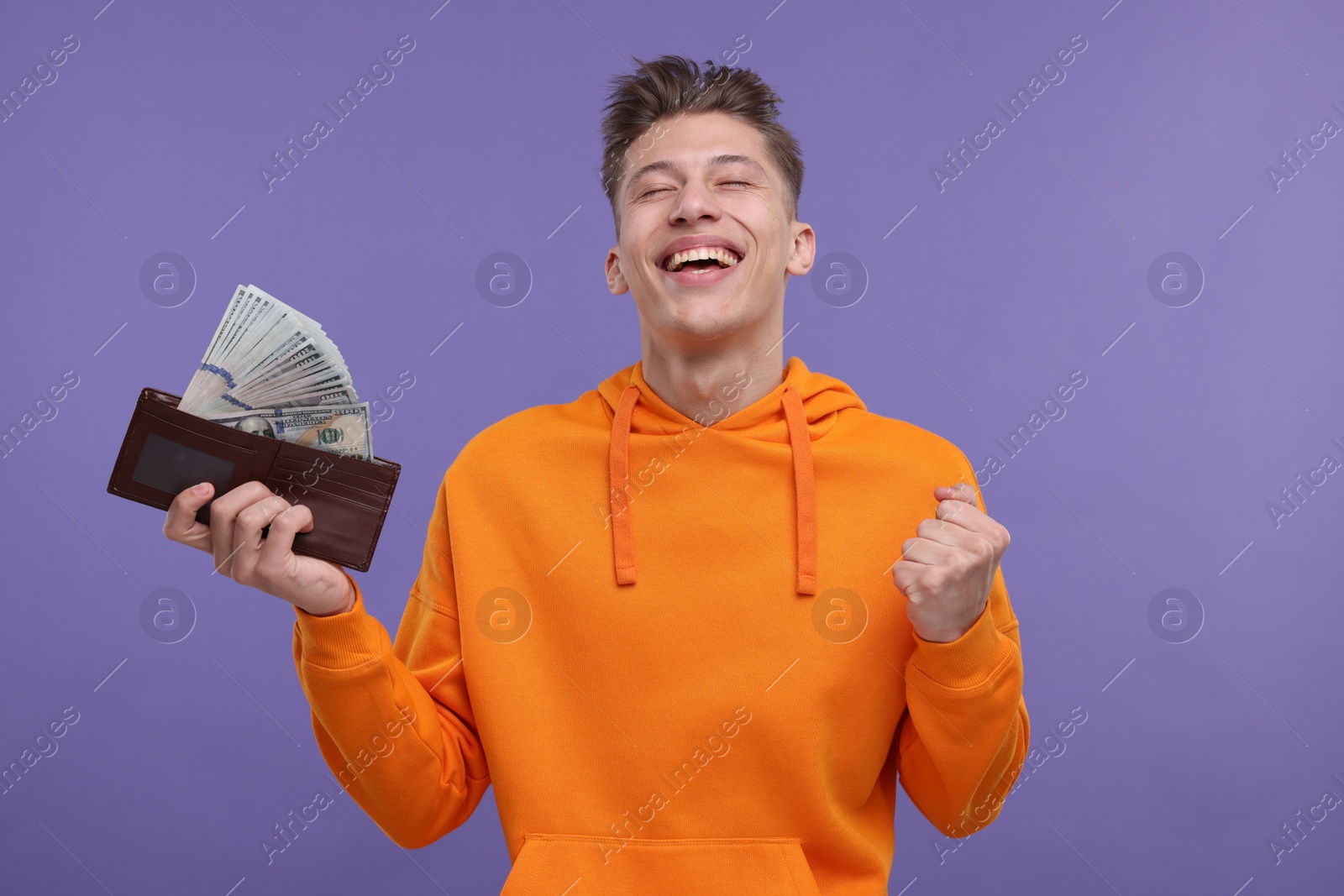 Photo of Happy man with money and wallet on purple background