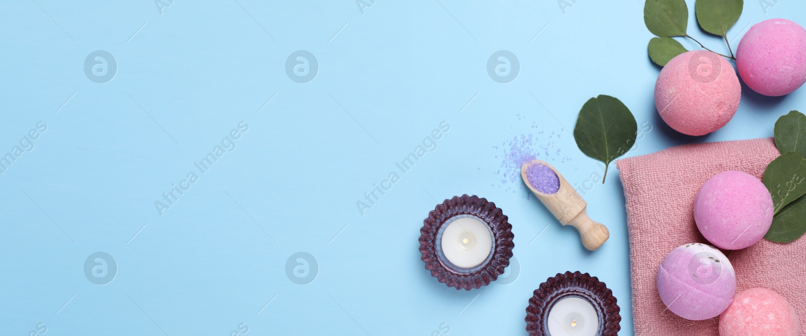 Photo of Bath bombs, eucalyptus leaves, burning candles and sea salt on light blue background, flat lay