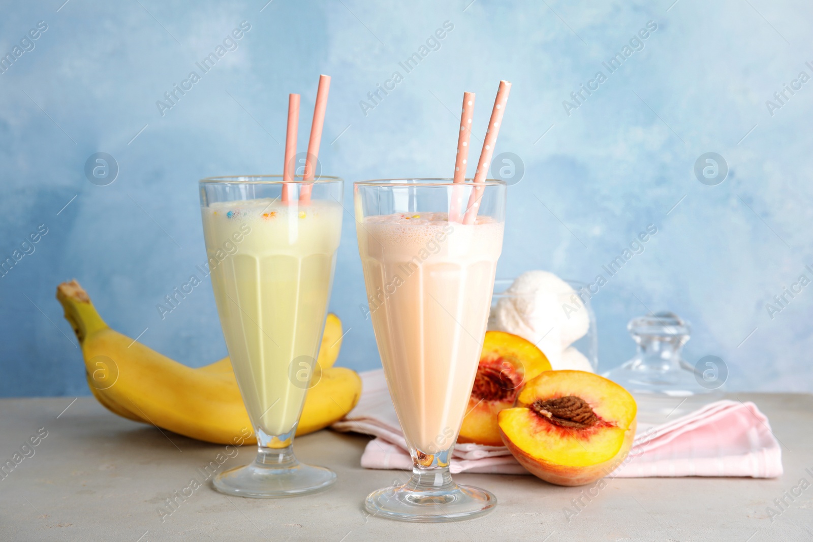 Photo of Delicious milk shakes and ingredients on table against color background
