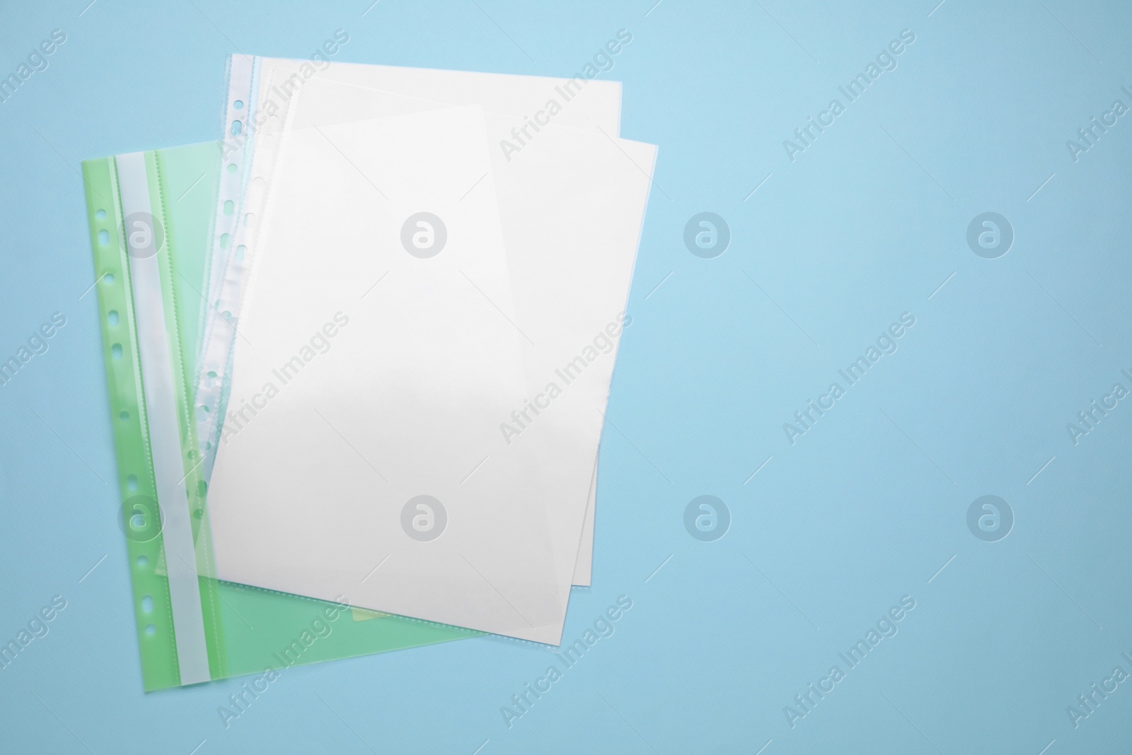 Photo of File folder with punched pockets and paper sheets on turquoise background, top view. Space for text