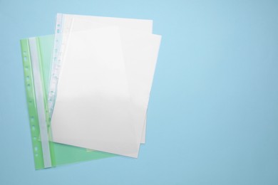 Photo of File folder with punched pockets and paper sheets on turquoise background, top view. Space for text