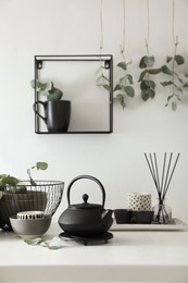 Stylish dishware and green eucalyptus branches on white table indoors