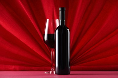 Photo of Stylish presentation of delicious red wine in bottle and glass on color background