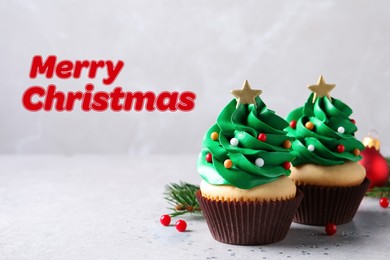 Image of Greeting card with phrase Merry Christmas. Festively decorated cupcakes on light grey table