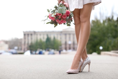 Young woman in elegant shoes walking on street