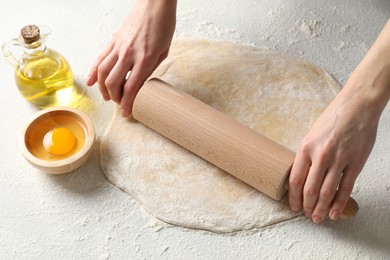 Photo of Woman rolling raw dough at table, closeup