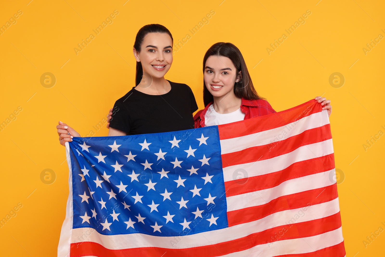 Photo of 4th of July - Independence Day of USA. Happy woman and her daughter with American flag on yellow background