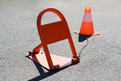Photo of Parking barrier with No Stopping road sign on it and traffic cone outdoors
