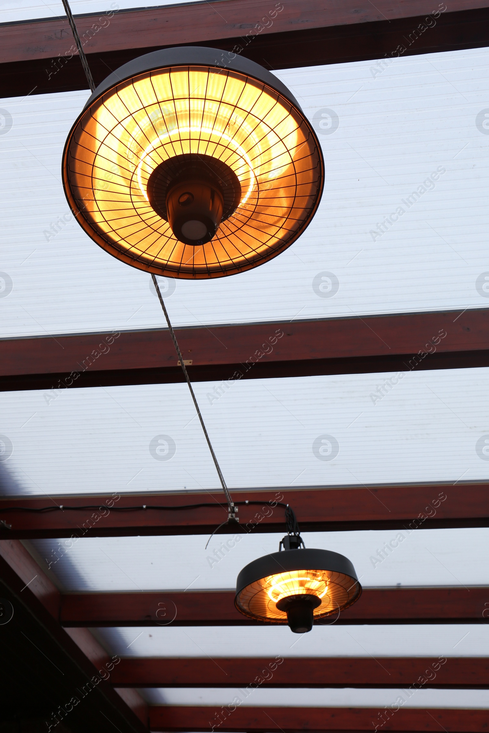 Photo of Stylish hanging infrared heaters on terrace indoors