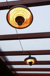 Photo of Stylish hanging infrared heaters on terrace indoors