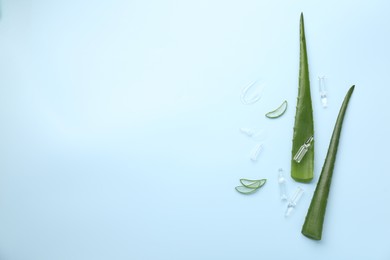 Photo of Flat lay composition with skincare ampoules and aloe leaves on light blue background. Space for text