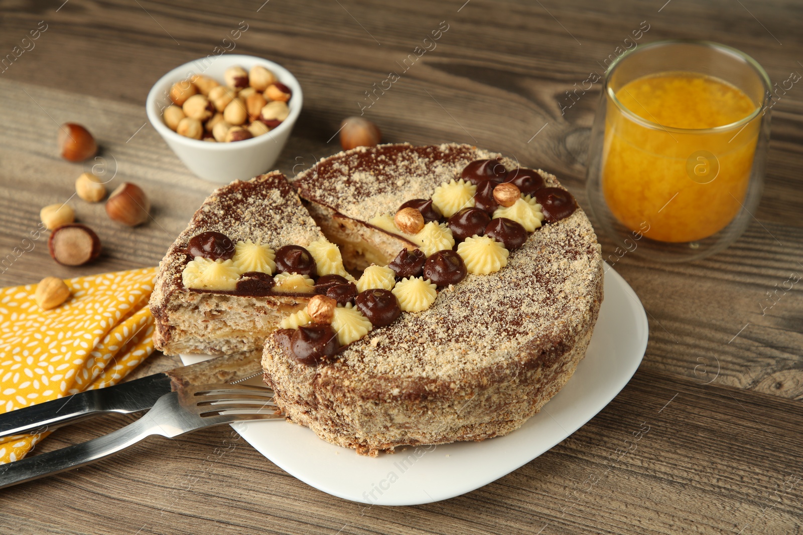 Photo of Delicious Kyiv Cake decorated with cream and hazelnuts served on wooden table