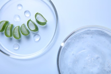 Photo of Cut aloe vera and cosmetic gel on light blue background, top view