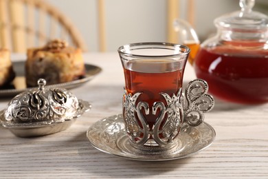 Photo of Traditional Turkish tea and sweets served in vintage tea set on white wooden table
