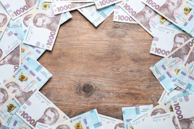 Photo of Frame of Ukrainian money on wooden background, flat lay. Space for text