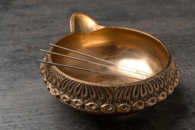 Photo of Golden bowl with needles for acupuncture on table