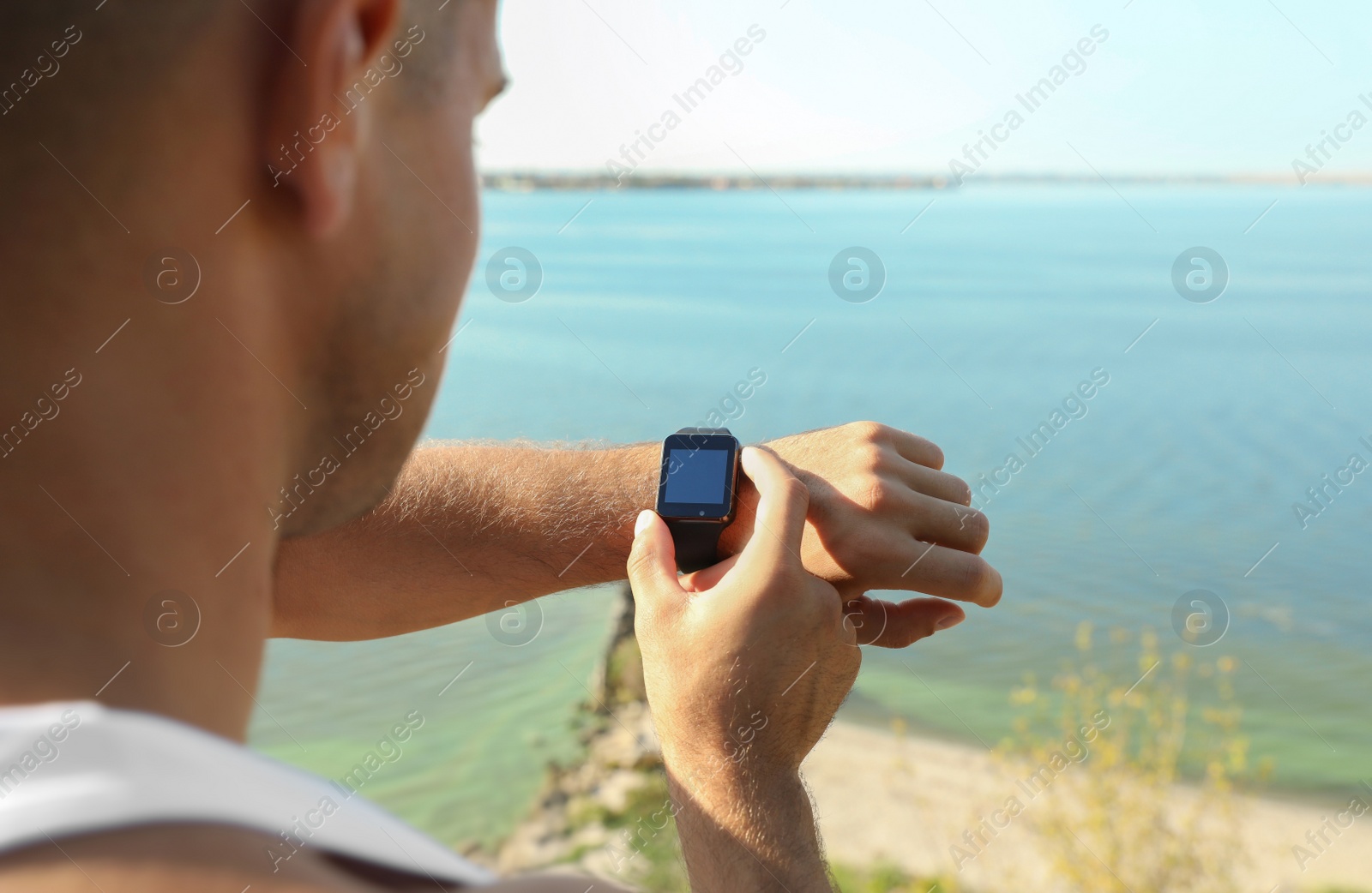 Photo of Man checking modern smart watch during training outdoors, closeup