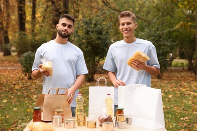 Portrait of volunteers packing food products at table in park