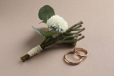Photo of Small stylish boutonniere and rings on beige background