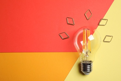 Photo of Flat lay composition with lightbulb on color background. Space for text
