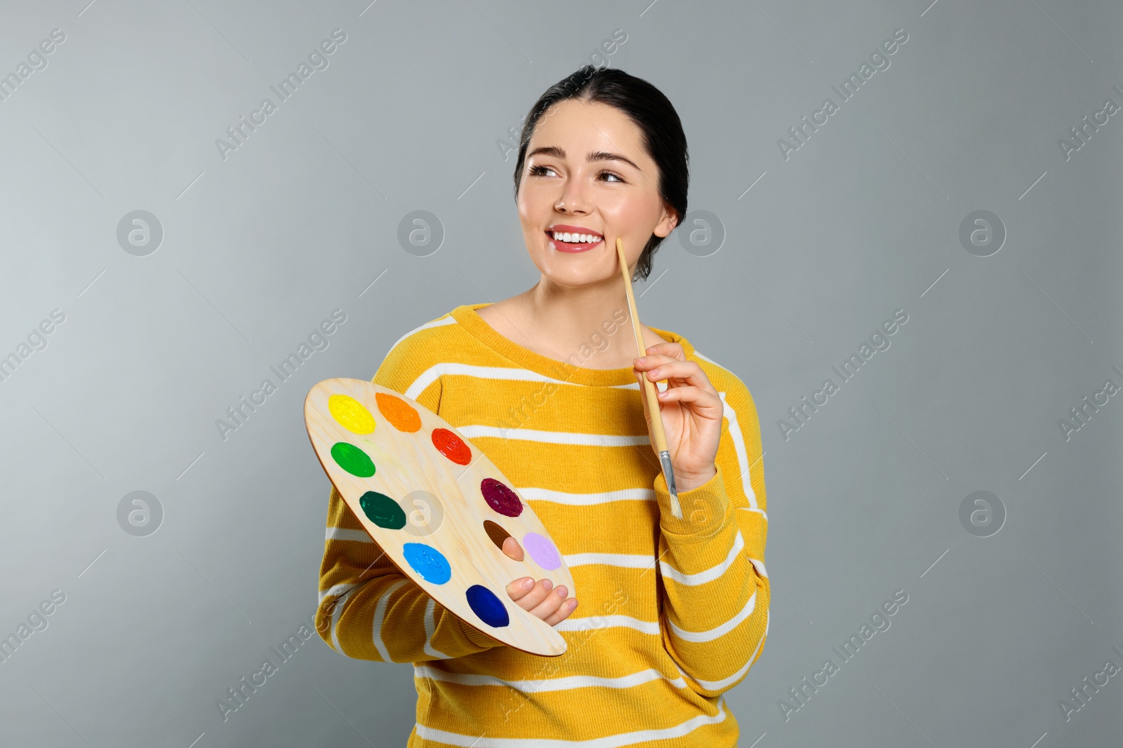 Photo of Woman with painting tools on grey background. Young artist