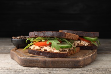 Delicious sandwiches with tuna and vegetables on wooden table