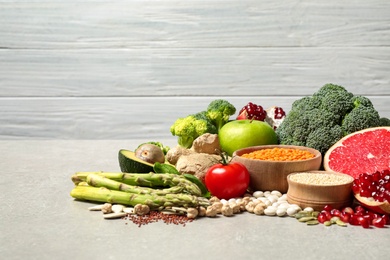 Photo of Fresh vegetables, fruits and seeds on grey table, space for text