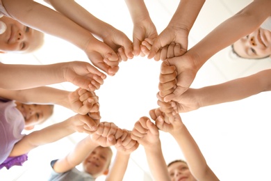 Little children putting their hands together indoors, view from below. Unity concept