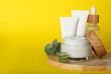 Photo of Body cream and other cosmetics, aloe with eucalyptus on yellow background. Space for text