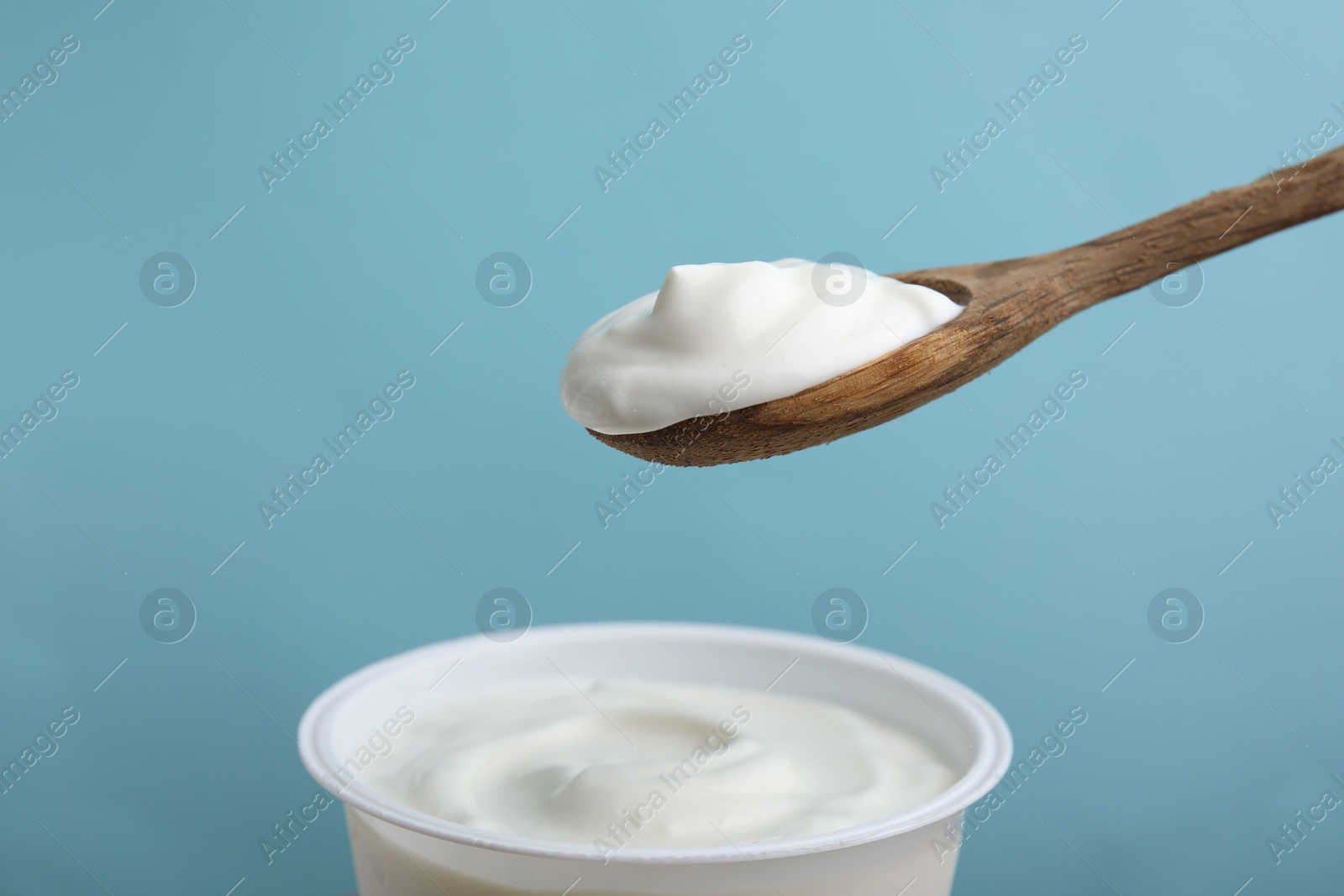 Photo of Eating delicious natural yogurt on light blue background