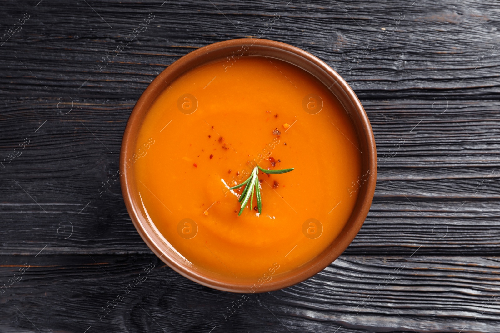 Photo of Bowl of tasty sweet potato soup on wooden table, top view
