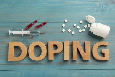 Word Doping and drugs on light blue wooden background, flat lay