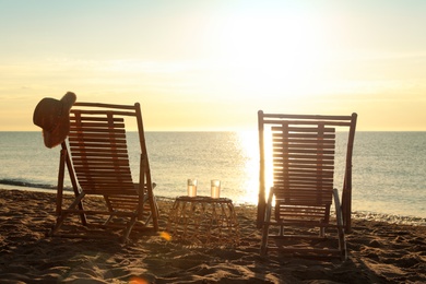 Photo of Wooden deck chairs and drinks near sea at sunset. Summer vacation
