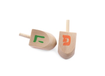 Photo of Wooden Hanukkah traditional dreidels with letters Pe and He on white background, top view
