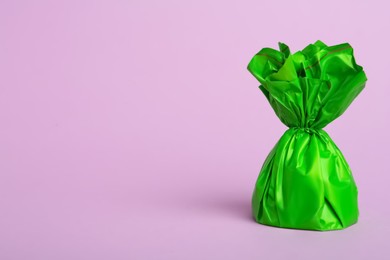 Photo of Candy in green wrapper on pink background. Space for text