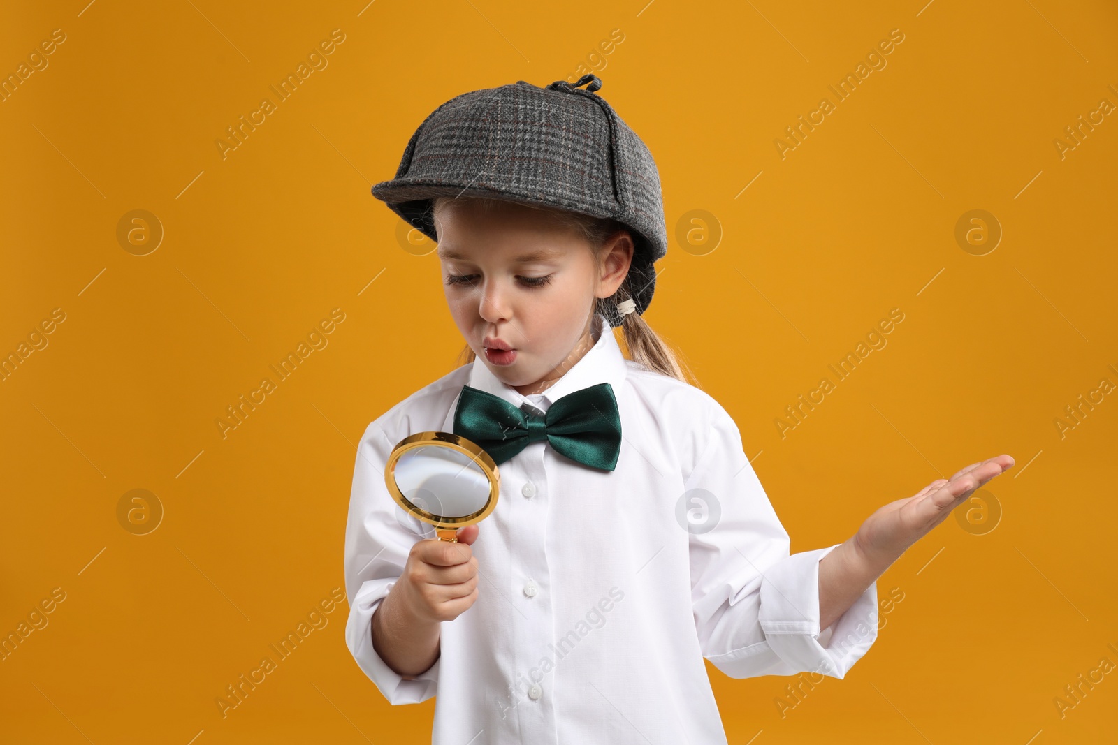 Photo of Cute little detective with magnifying glass on yellow background