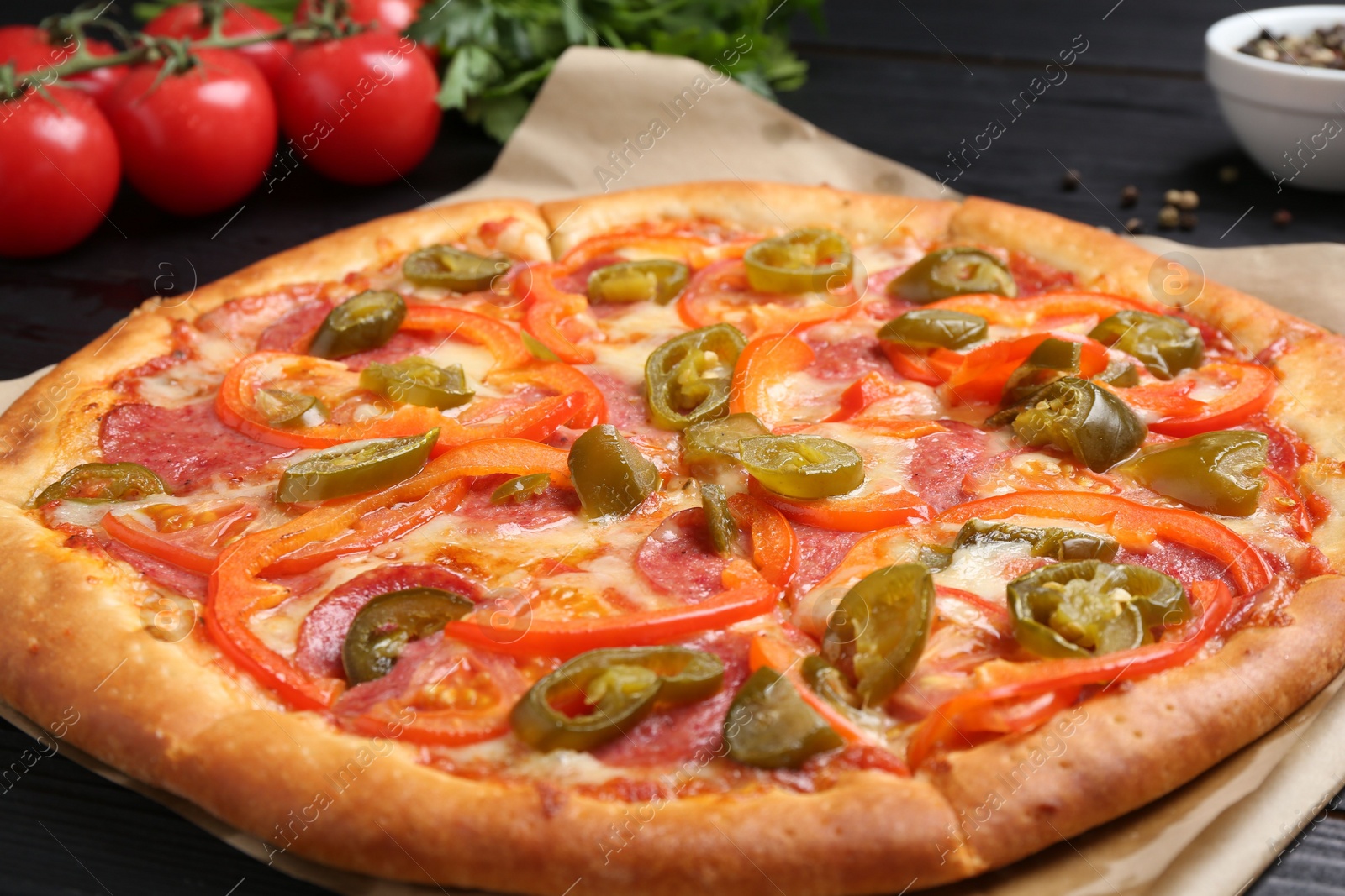 Photo of Delicious pizza Diablo and ingredients on black wooden table, closeup