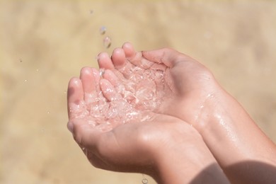 Photo of Pouring water into kid`s hands outdoors, closeup