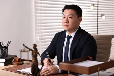 Notary writing notes at wooden table in office