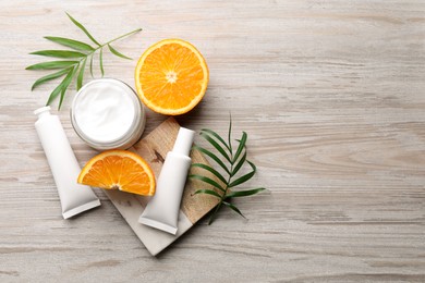 Photo of Different hand care cosmetic products, orange and green leaves on white wooden table, flat lay. Space for text
