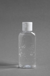 Transparent bottle with cosmetic product on grey background