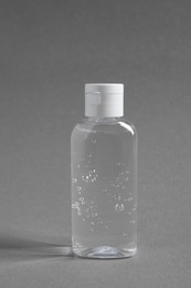 Photo of Transparent bottle with cosmetic product on grey background