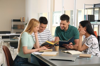 Photo of Young people discussing group project at table in library